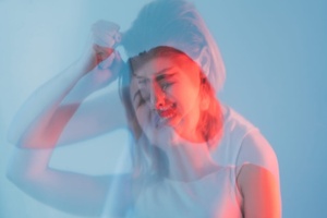 Young woman sitting alone looking distressed and withdrawn, representing early symptoms of schizophrenia in females
