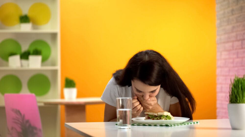 Young woman looking at food with anxiety, highlighting eating disorder challenges