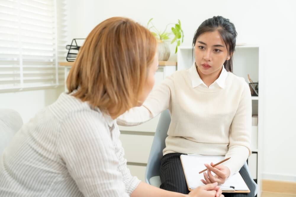 Mental health professional discussing symptoms with adult patient during ADHD testing appointment in clinical office setting.