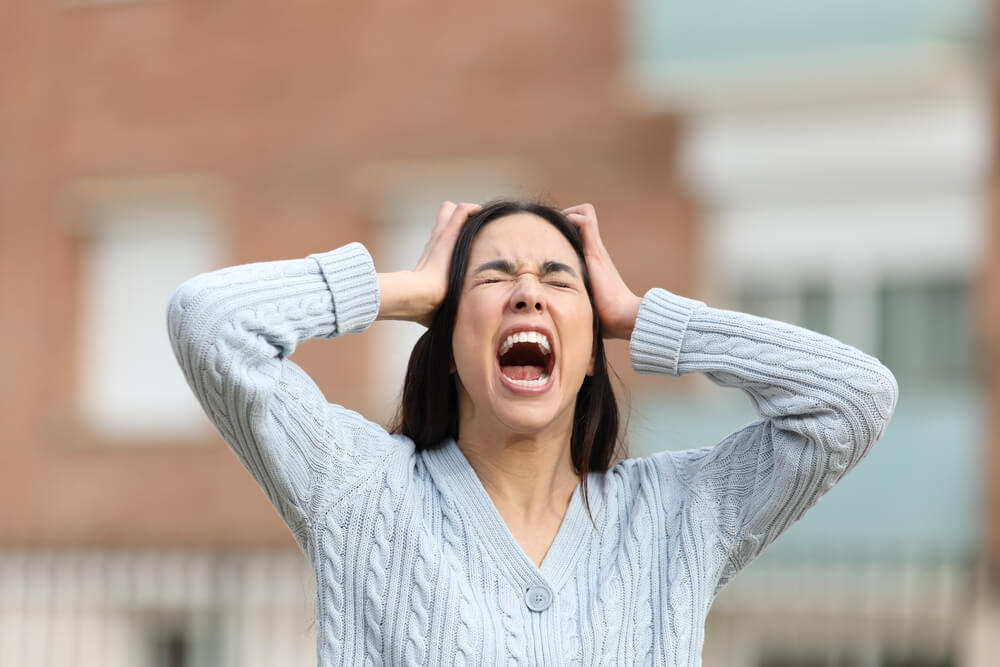 Woman covering ears due to auditory hallucinations, a common symptom of paranoid schizophrenia