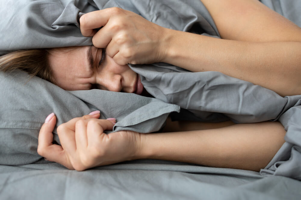 Close-up of person clutching tightly and restlessly with rapid heartbeat and shortness of breath at nigh, due to panic attack in sleep