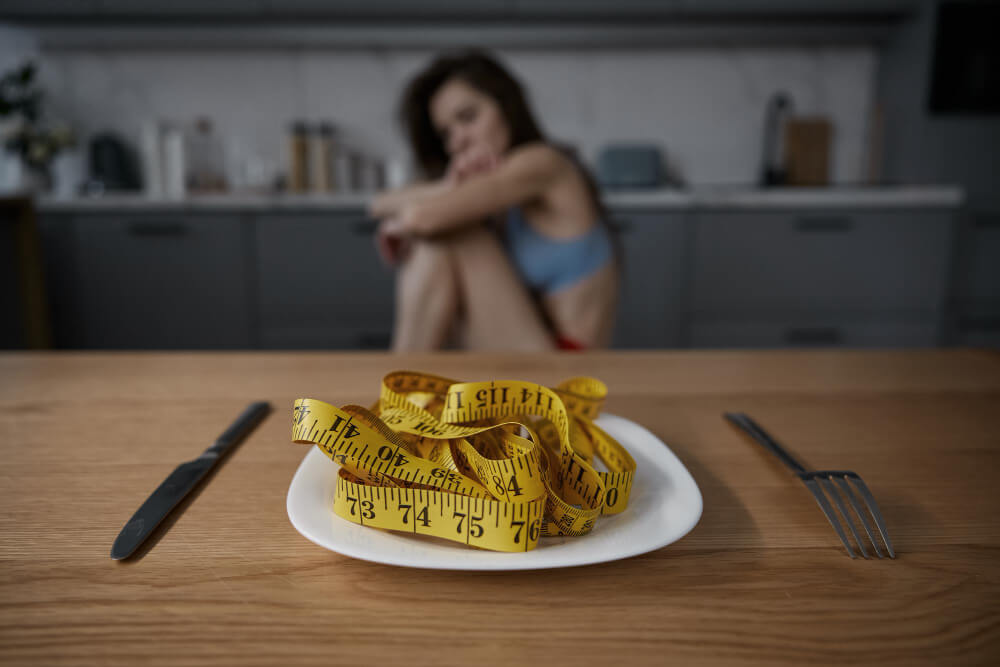very waek Young woman sitting alone looking emotionally distressed due to anorexia nervosa and mental health struggles.